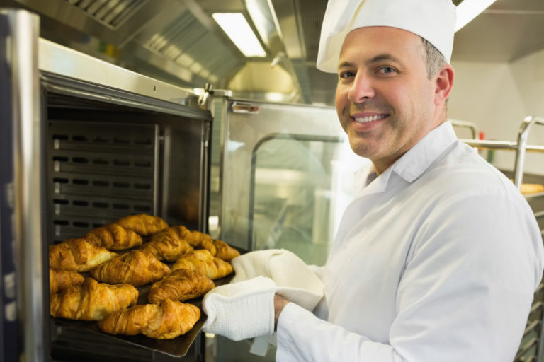 baker putting his breads in the oven
