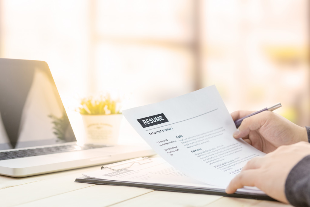 person writing or reviewing their resume with laptop in front